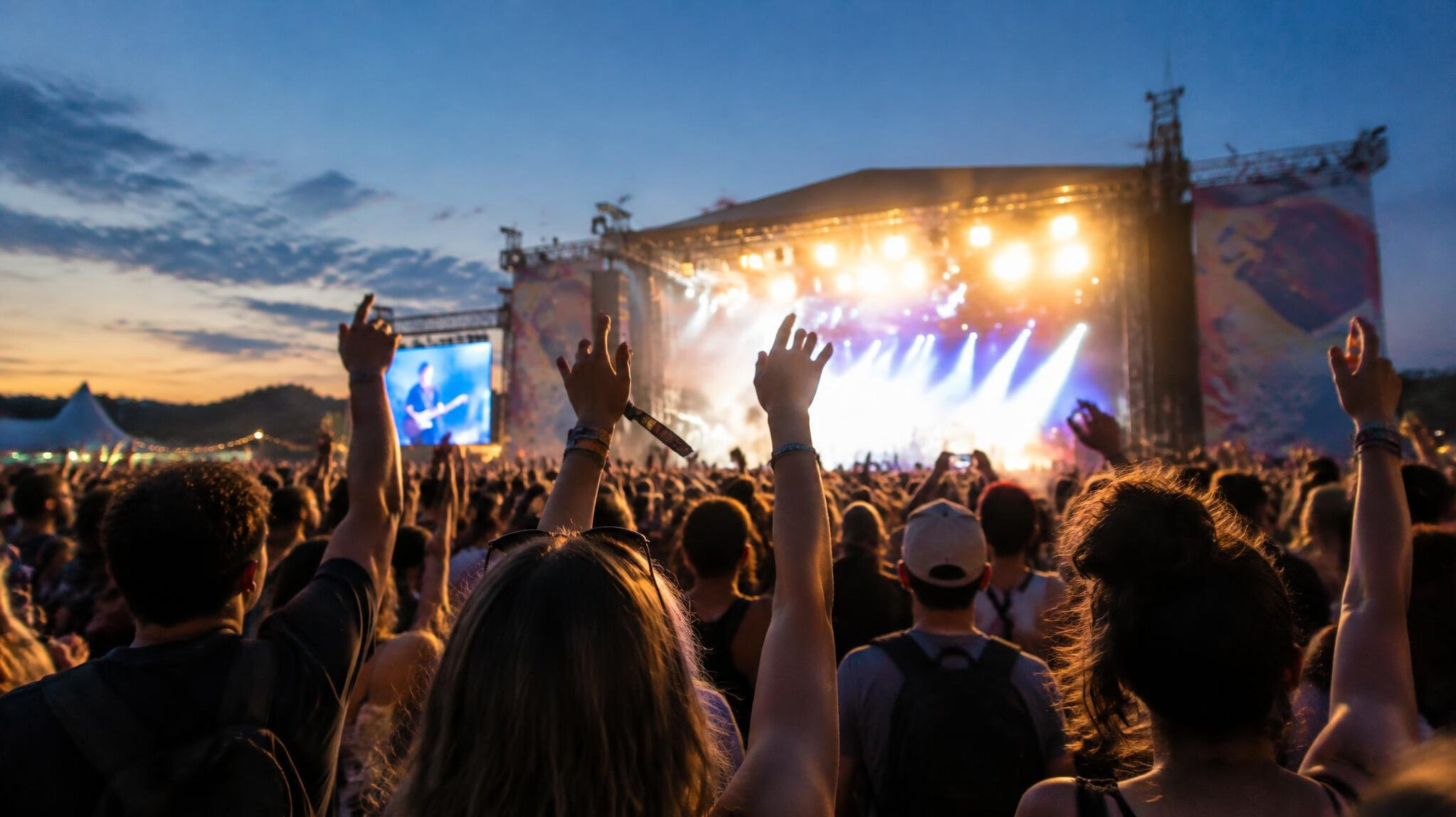 Concert crowd seen from behind facing a bright stage